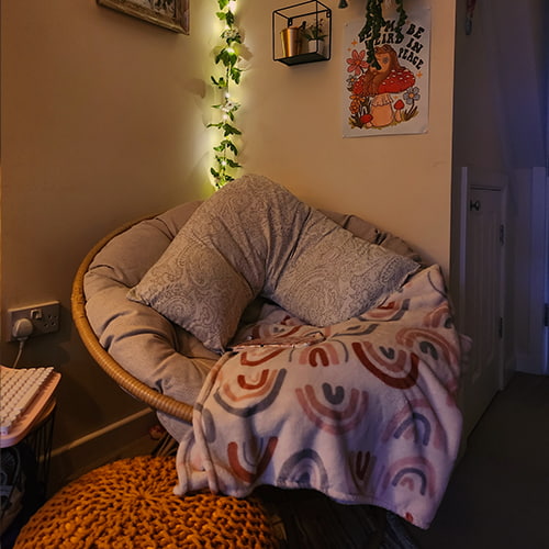 Cosy hobbies corner. Welcoming chair in corner of living-room with blanket and pillows.